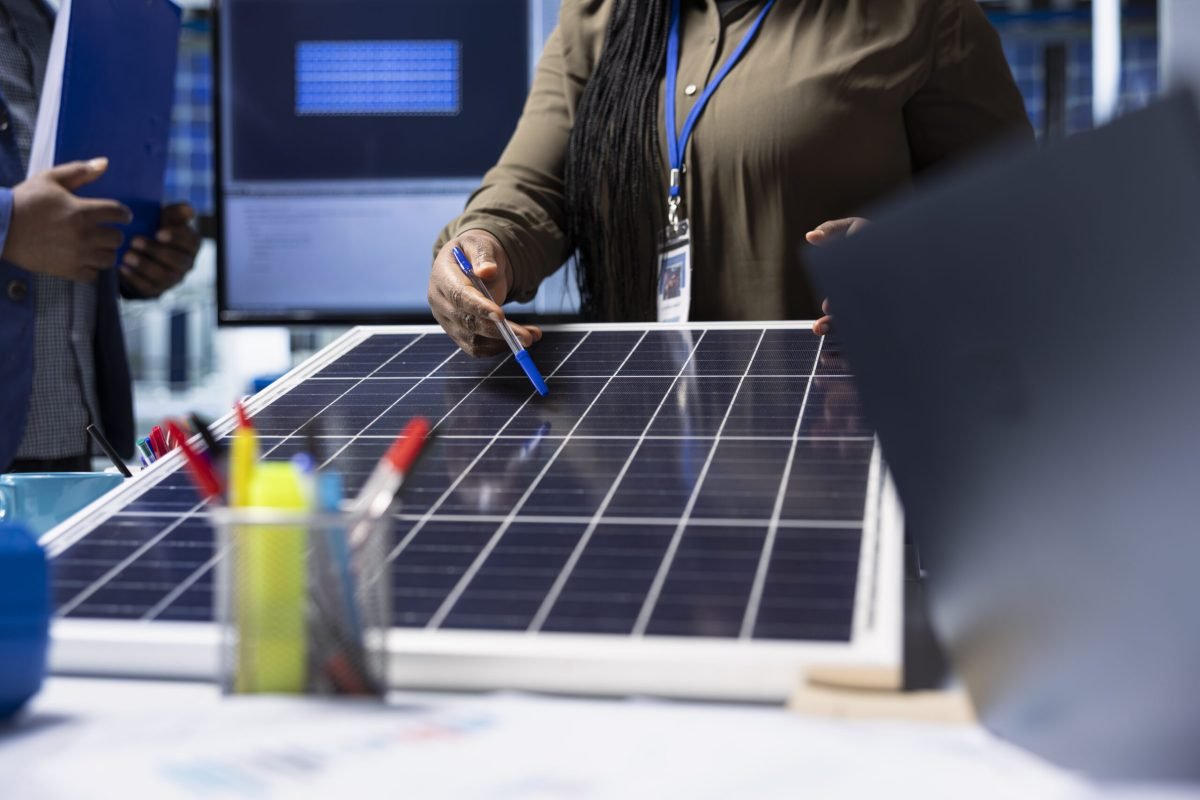 Shareholders meet with industrial plant manager to review solar panel components, analyzing material quality. Photovoltaics factory management executive presents solar panel features to investors